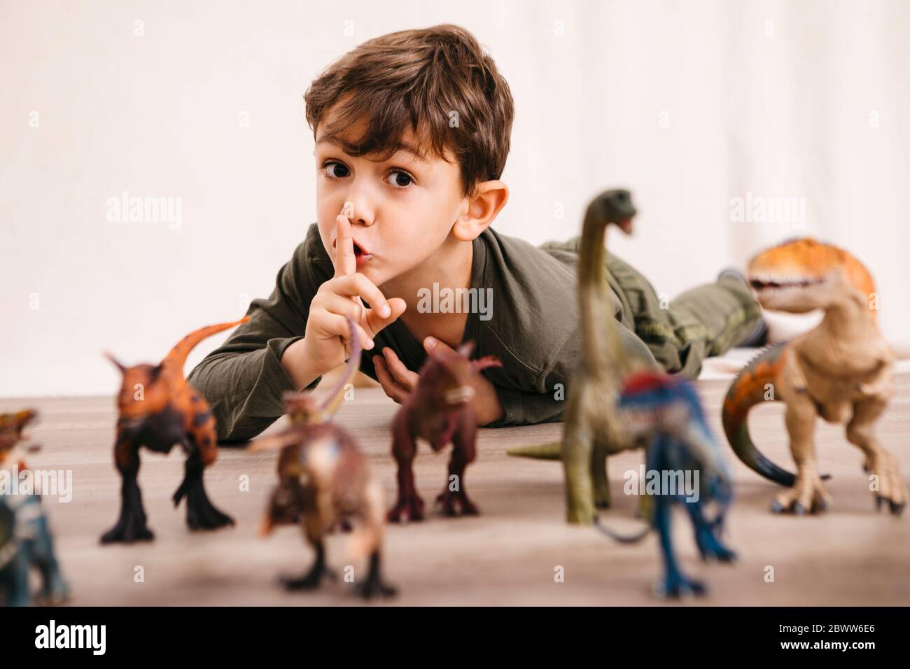 Portrait des kleinen Jungen, der mit Spielzeug-Dinosaurier spielt Stockfoto