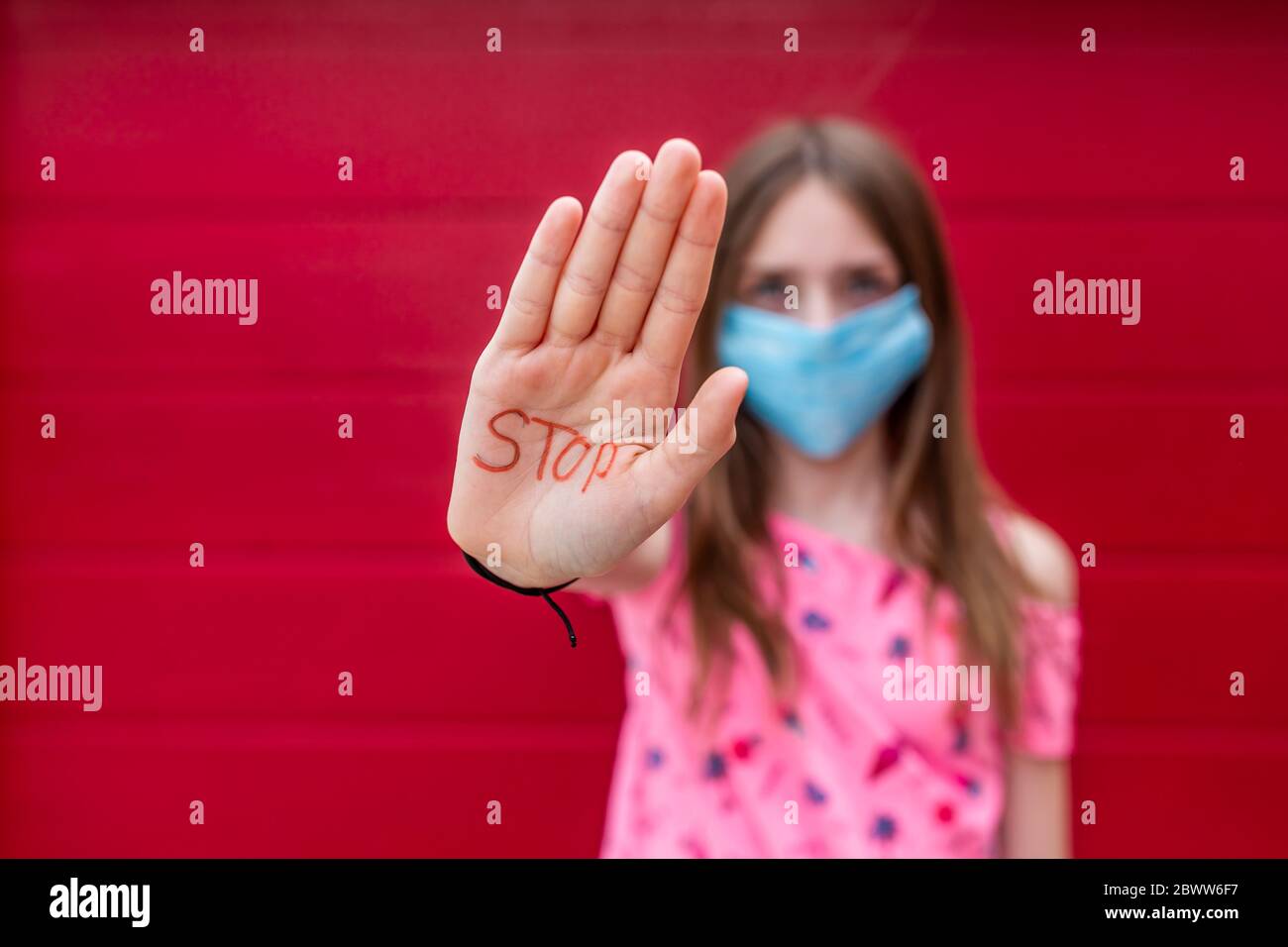 Mädchen mit Gesichtsmaske zeigt Handfläche ihrer Hand, sagen Stopp Stockfoto