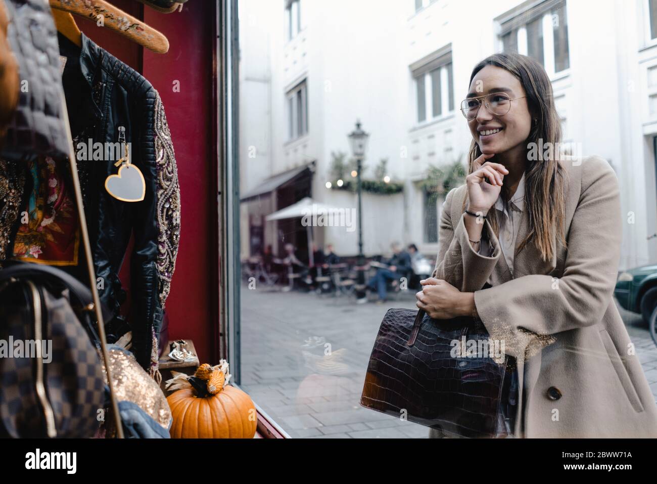 Lächelnde Frau mittleren Erwachsenen Blick auf Schaufenster des Geschäfts in der Stadt Stockfoto