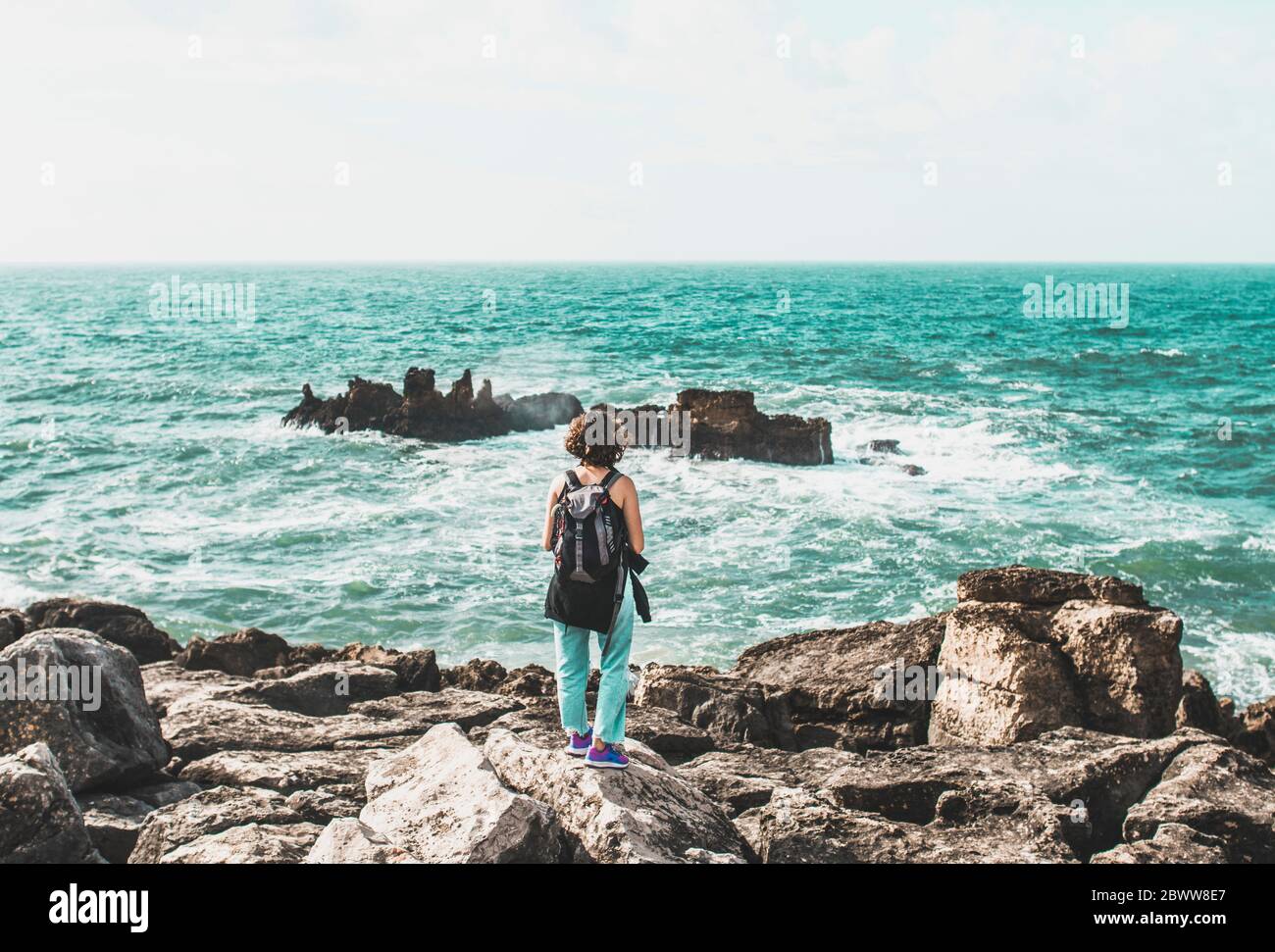 Portugal, Lissabon, Sintra, Junge Frau bewundern türkisfarbenes Wasser des Atlantischen Ozeans von der felsigen Küste von Cabo da Roca Stockfoto