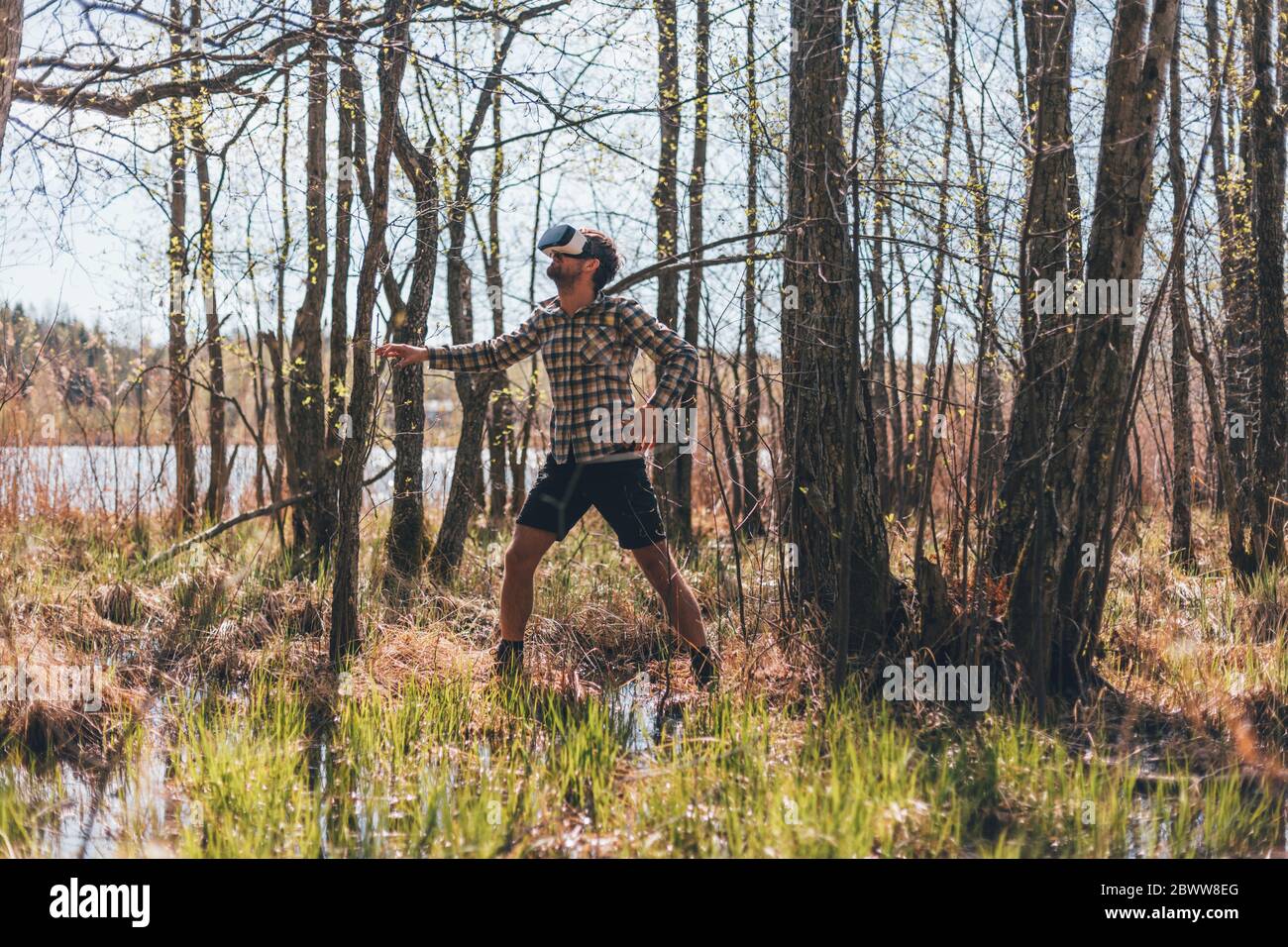 Junger Mann, der mit VR-Brille im Wald Spiele Stockfoto