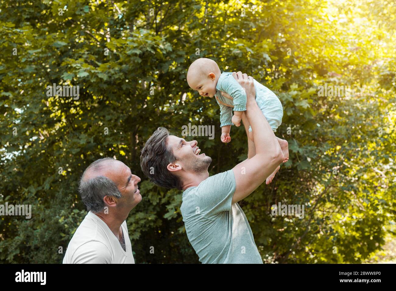 Älterer Mann verbringt Zeit mit seinem erwachsenen Sohn und seiner Enkelin in einem Park Stockfoto