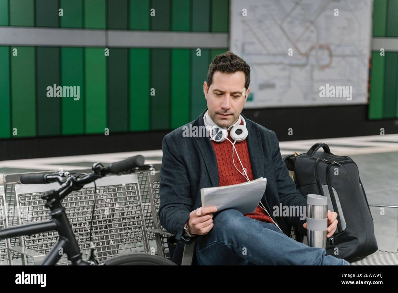 Geschäftsmann mit Fahrrad-Leseunterlagen während der Sitzung am U-Bahn-Bahnsteig, Frankfurt, Deutschland Stockfoto