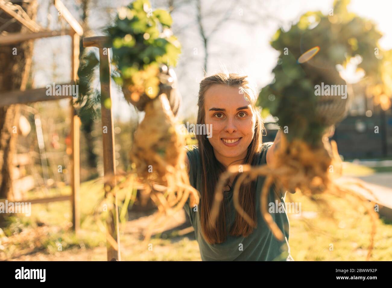 Stolze junge Frau, die im Garten Sellerie hält Stockfoto