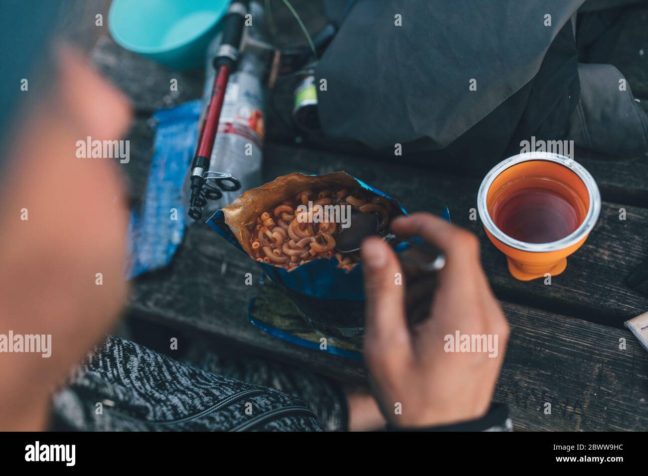 Junger Mann, der auf einem Ausflug im Freien ein Convenience Food isst, Nahaufnahme Stockfoto