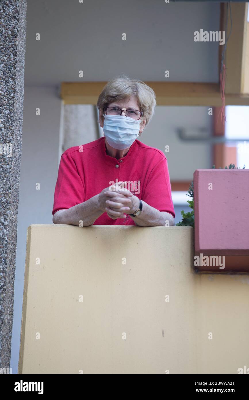 Ältere Frau trägt Maske auf Balkon, Altersheim Stockfoto