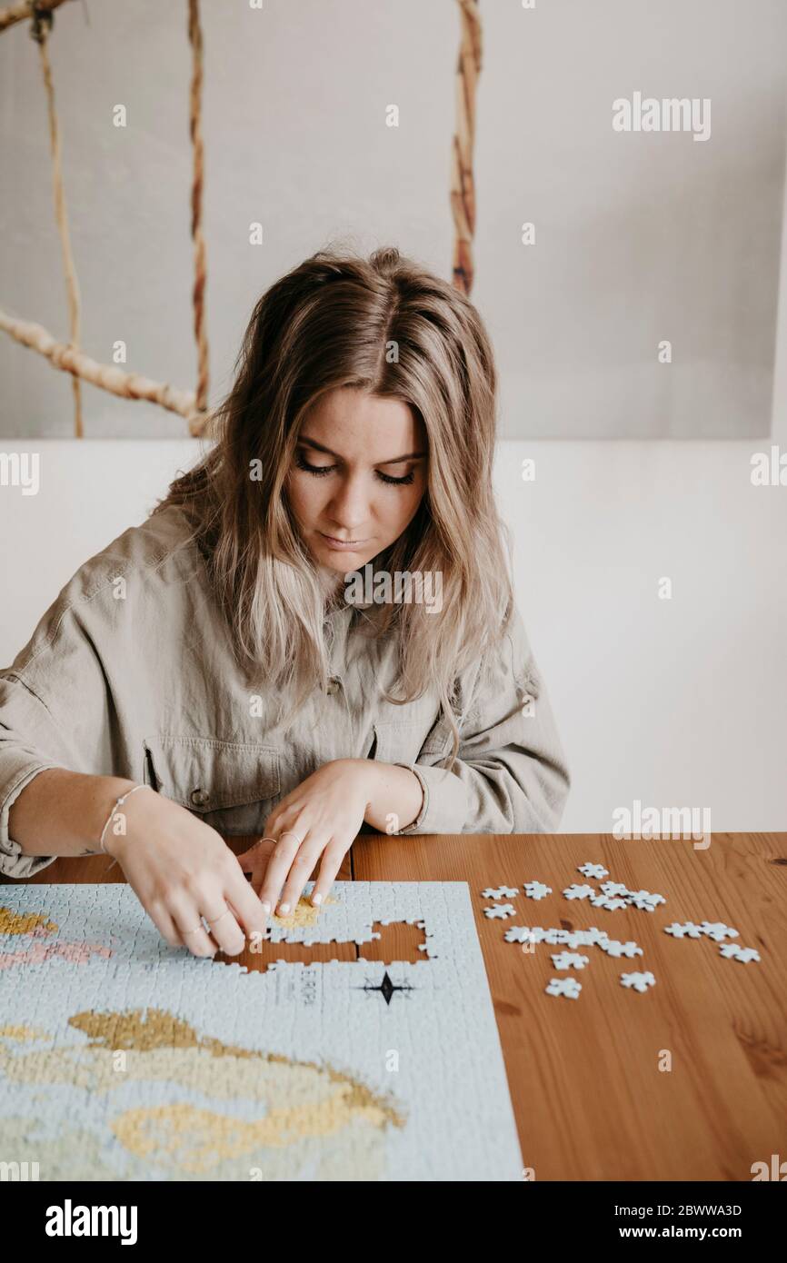 Frau spielt mit Puzzle am Tisch während der Quarantäne zu Hause Stockfoto