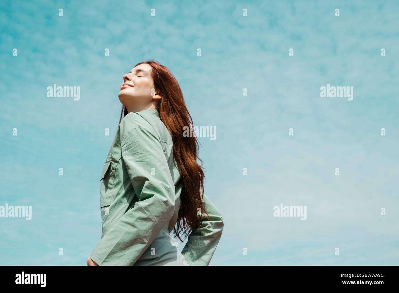 Porträt einer rothaarigen jungen Frau mit geschlossenen Augen gegen den Himmel Stockfoto