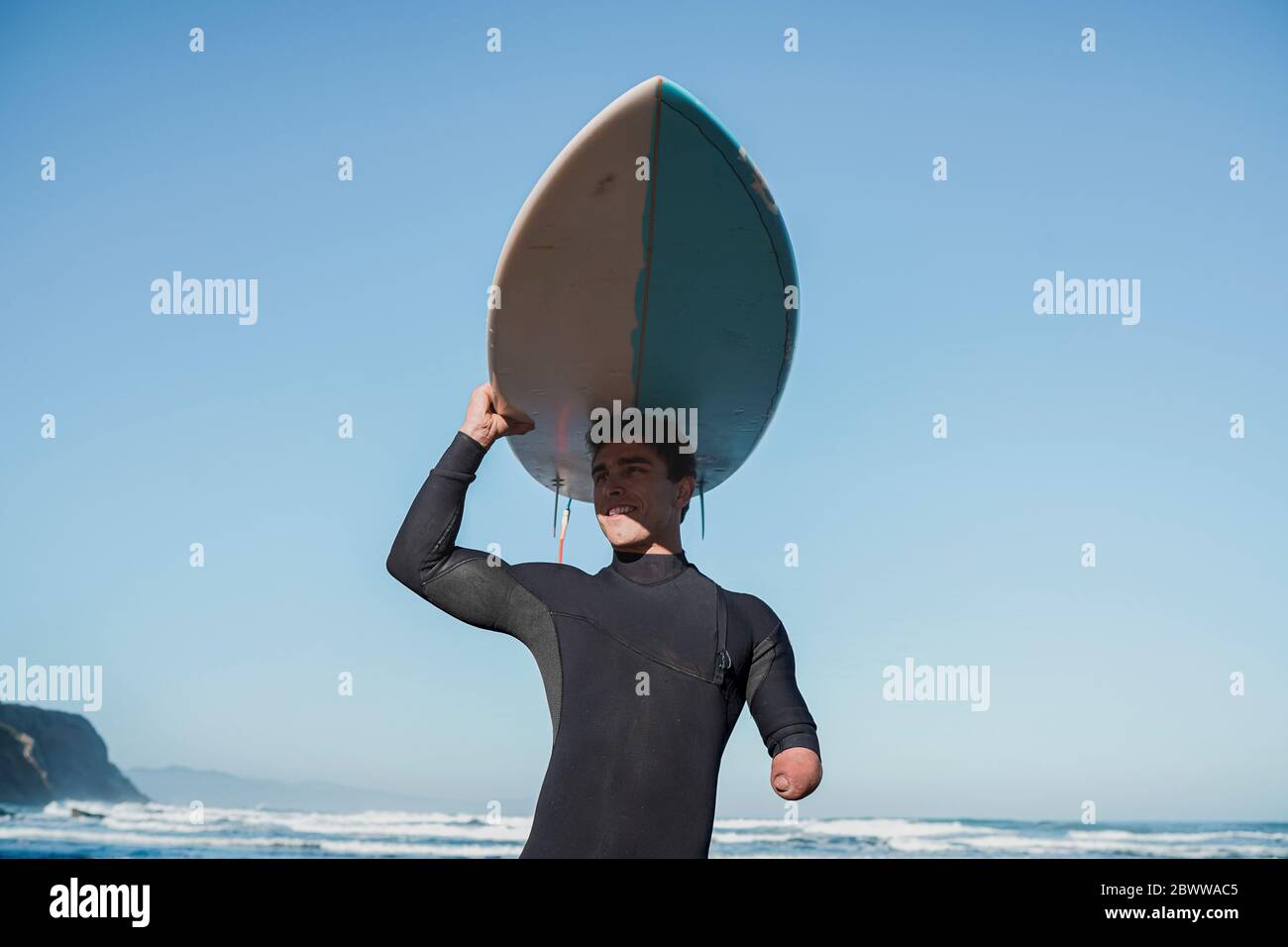 Behinderter Surfer, der sein Surfbrett auf dem Kopf trägt Stockfoto