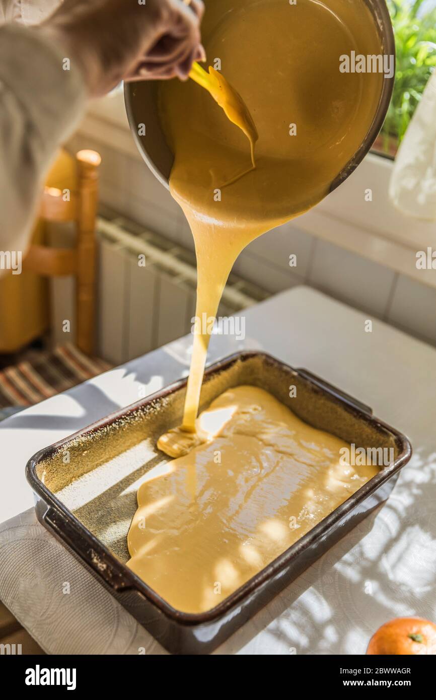 Hand der Frau Gießen gemischte Kuchen Zutaten in Backform Stockfoto