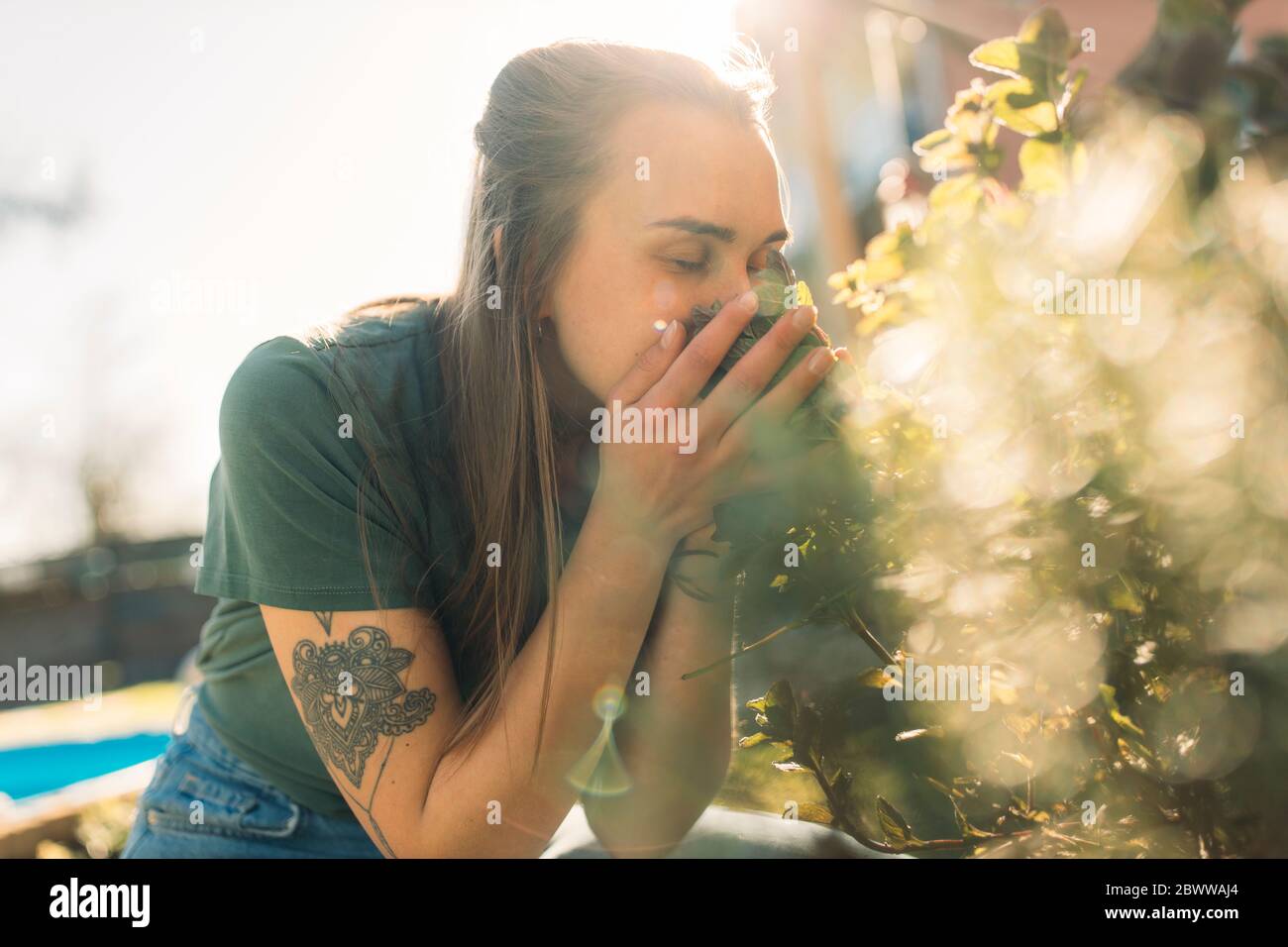 Junge Frau riecht nach Kräutern im Garten Stockfoto