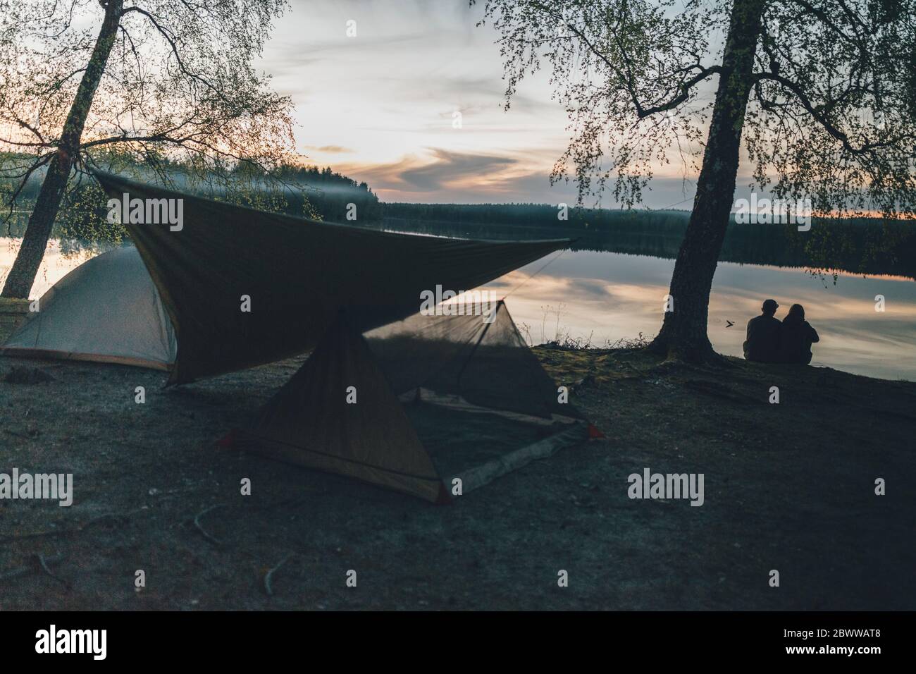 Pärchen campen am See und schauen auf den Sonnenuntergang Stockfoto