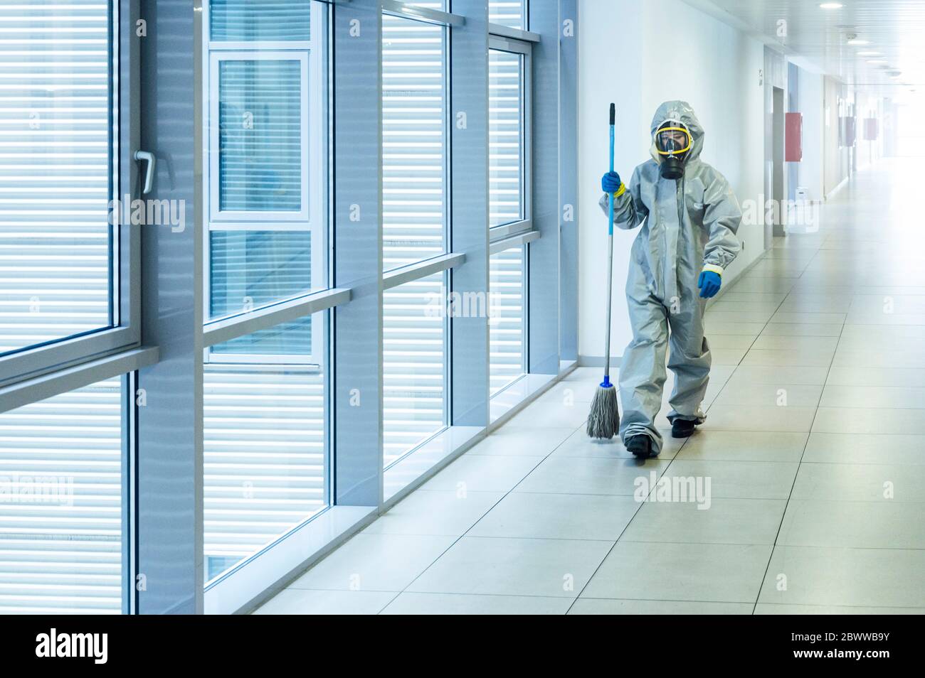 Reinigungspersonal läuft mit Reinigungsmopp im Flur, trägt Schutzkleidung Stockfoto