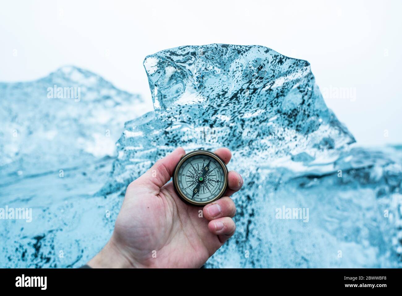 Island, Hand des Menschen mit Kompass vor großen Eisblock Stockfoto