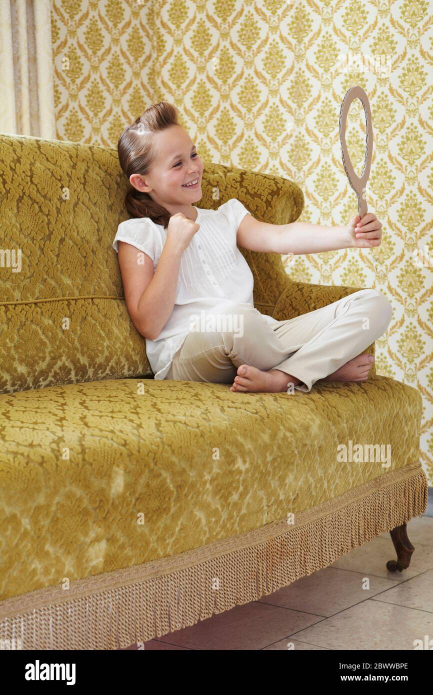 Happy girl sitzt auf einer Couch suchen in Pappe Spiegel Stockfoto
