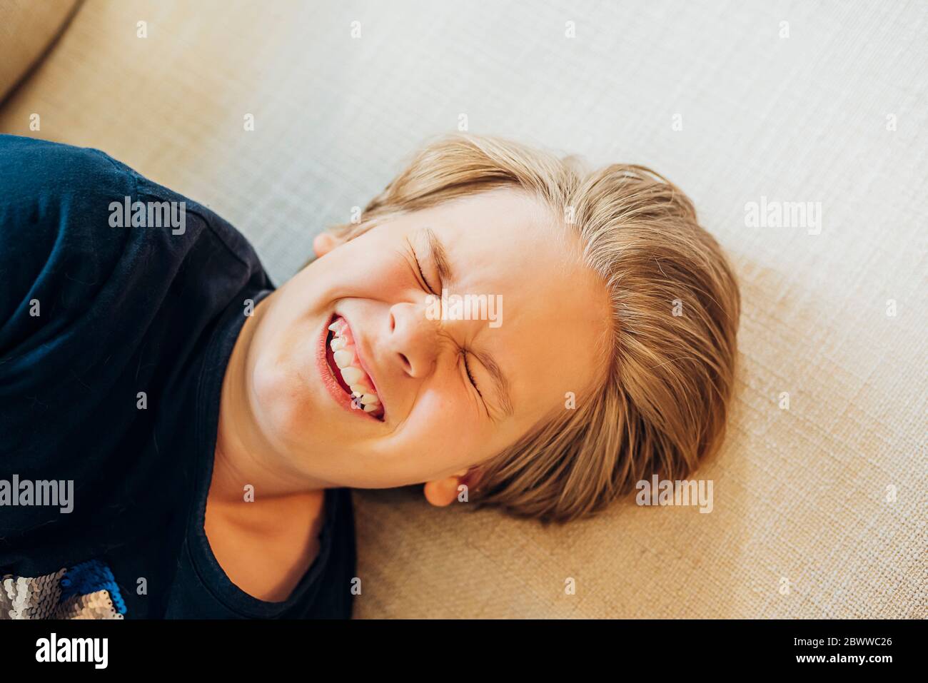 Draufsicht auf verspielten Jungen auf der Couch liegen Stockfoto