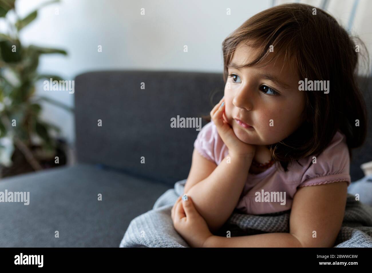 Portrait des Mädchens, das zu Hause auf der Couch sitzt Stockfoto