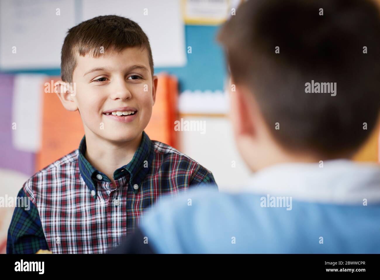 Porträt eines lächelnden Jungen, der im Klassenzimmer einen Klassenkameraden ansieht Stockfoto