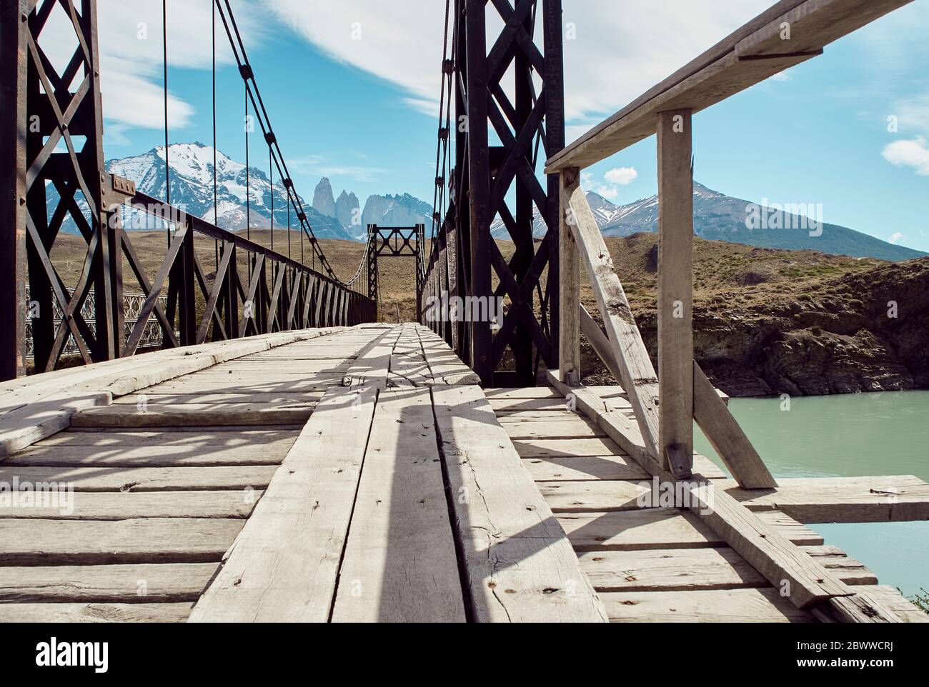 Eisen- und Holzbrücke auf dem Wasser und Torres del Paine Berge im Hintergrund, Parque Nacional Torres del Paine, Chile Stockfoto