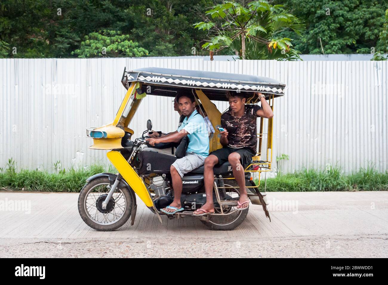 Das berühmte philippinische Dreirad oder Tuk Tuk (manchmal auch Rikscha genannt) macht seinen Weg entlang der viel befahrenen Hauptstraße, die in Coron Town eigentlichen. Coron Island. Stockfoto