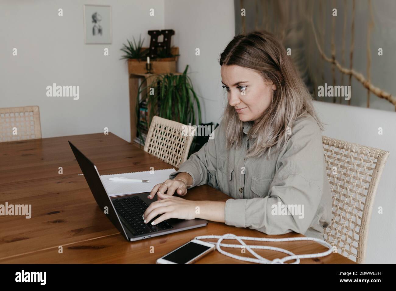 Frau mit Laptop, während sie am Tisch im Esszimmer während der Quarantäne zu Hause sitzt Stockfoto