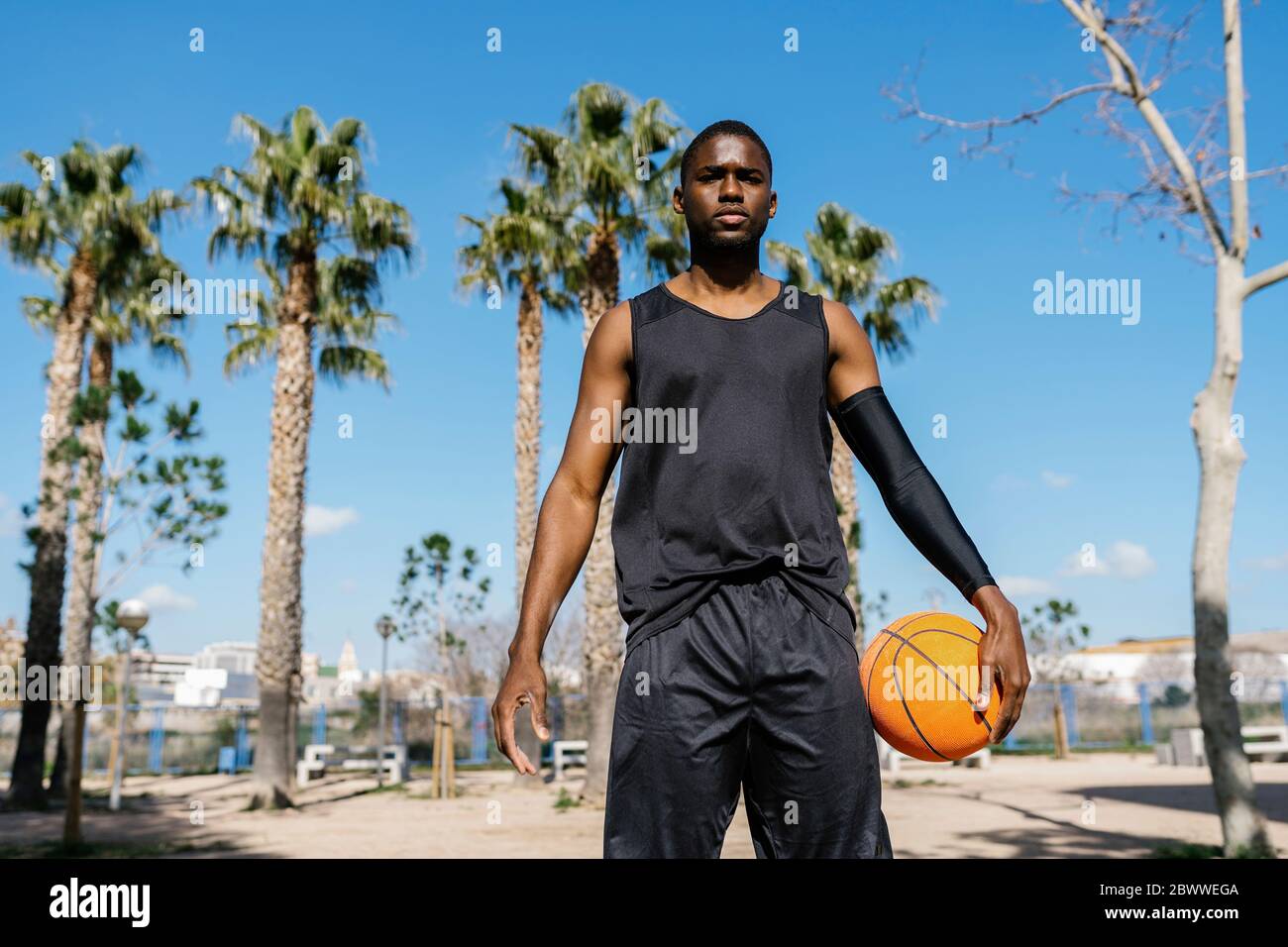 Junger Mann hält Basketball auf dem Basketballplatz stehen Stockfoto