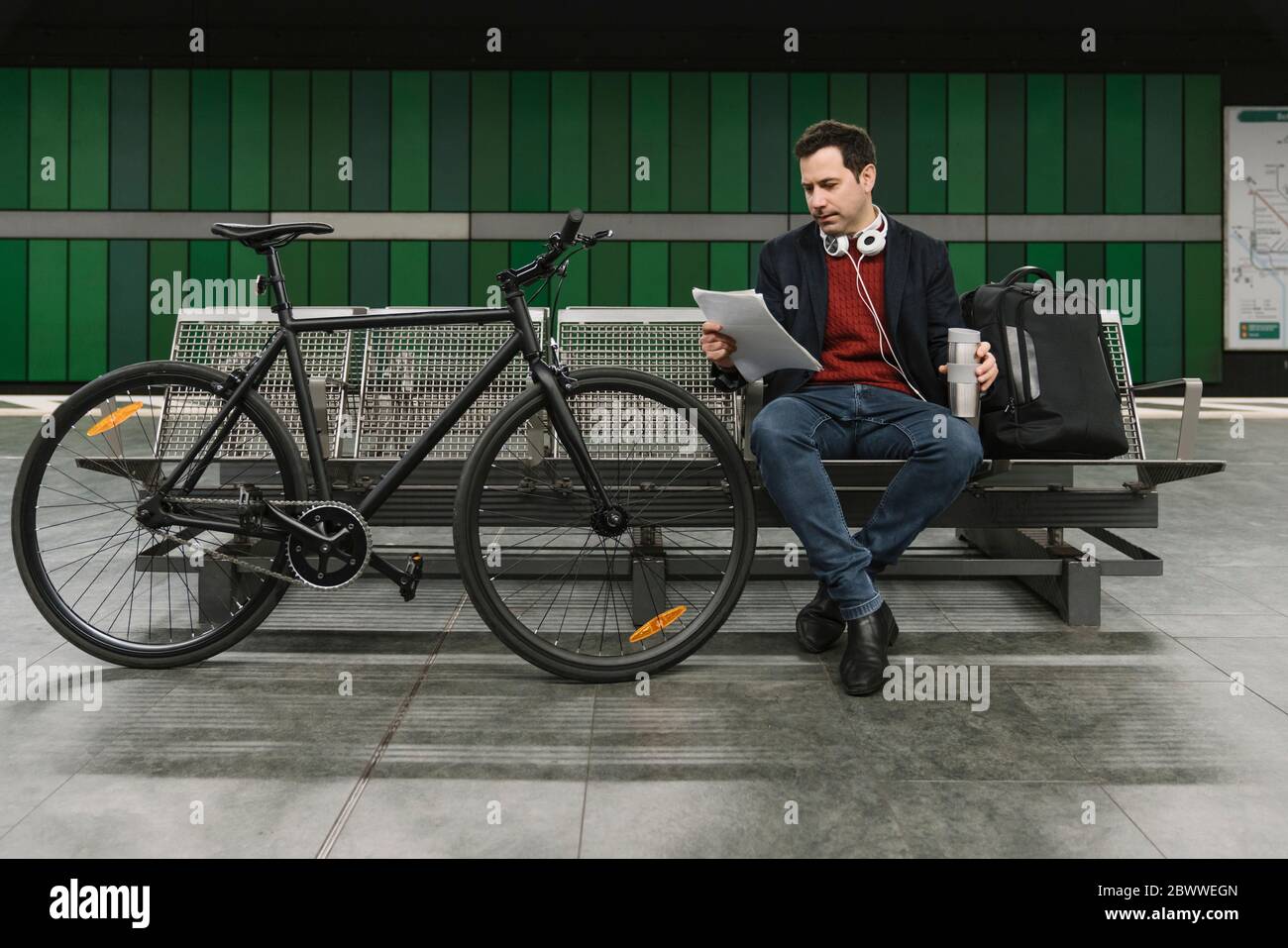 Geschäftsmann mit Fahrrad-Leseunterlagen während der Sitzung am U-Bahn-Bahnsteig, Frankfurt, Deutschland Stockfoto