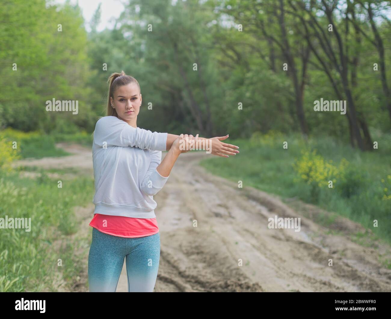 Junge Blonde Kaukasische Weibliche Forest Runner Stretching Stockfoto