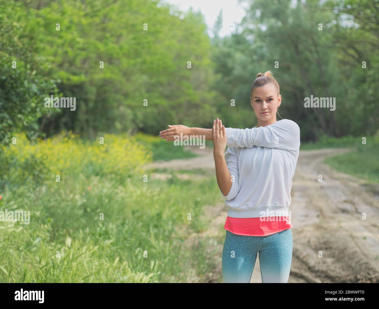 Junge Blonde Kaukasische Weibliche Forest Runner Stretching Stockfoto