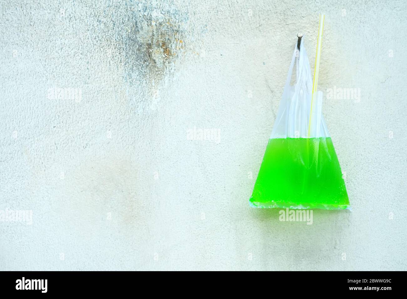 Grüne Soda mit Stroh in Plastiktüte Aufhängen an alte Betonwand  Stockfotografie - Alamy