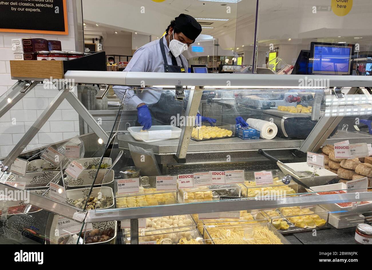 Ein Mitarbeiter arbeitet hinter einem Schutzschirm an der Käsetheke in der Lebensmittelhalle in Selfridges, London, nachdem Maßnahmen eingeführt wurden, um England aus der Sperre zu holen. Stockfoto
