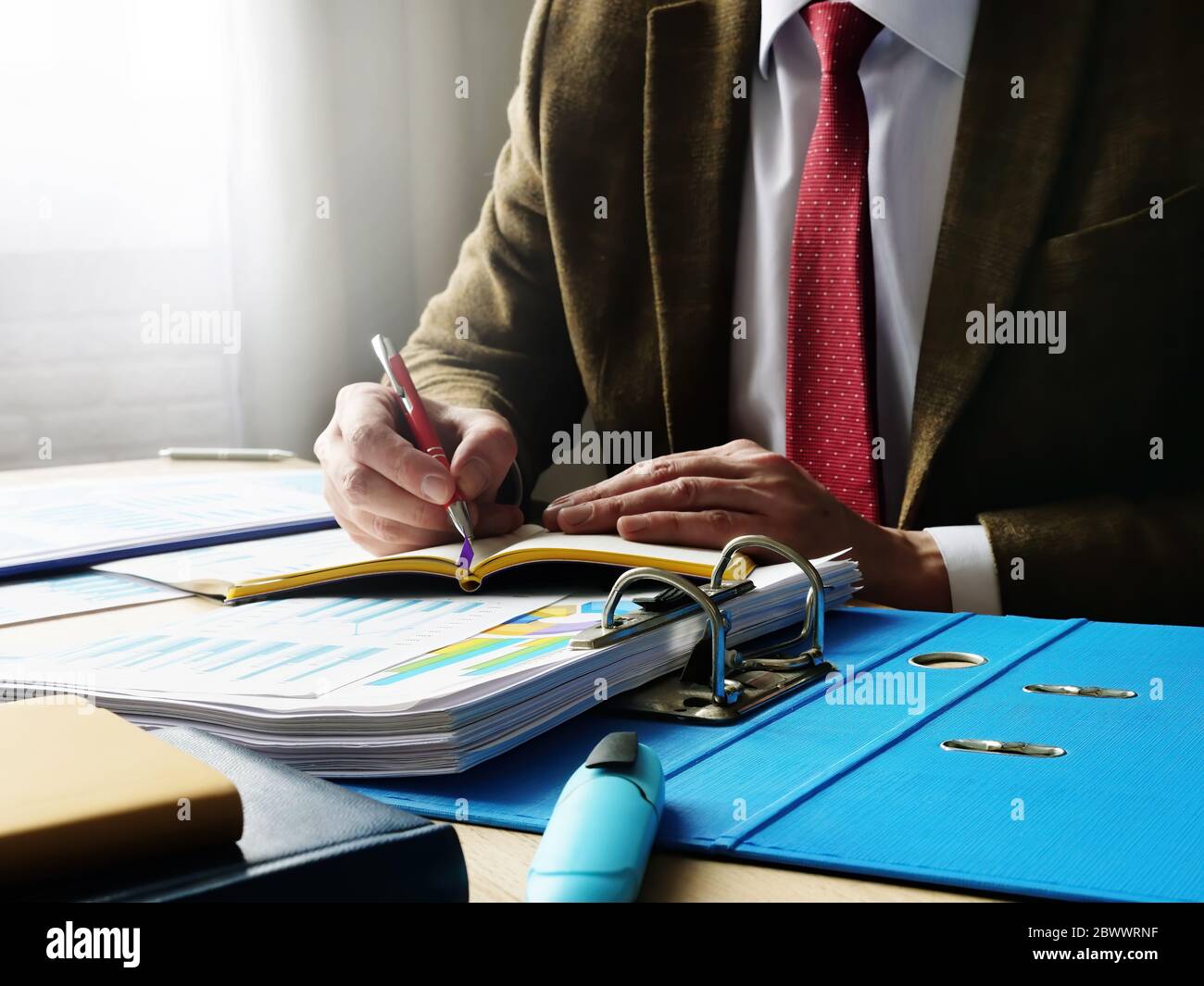 Geschäftsmann oder Buchhalter macht Notizen in einem Notizbuch. Unterlagen mit Dokumenten. Stockfoto