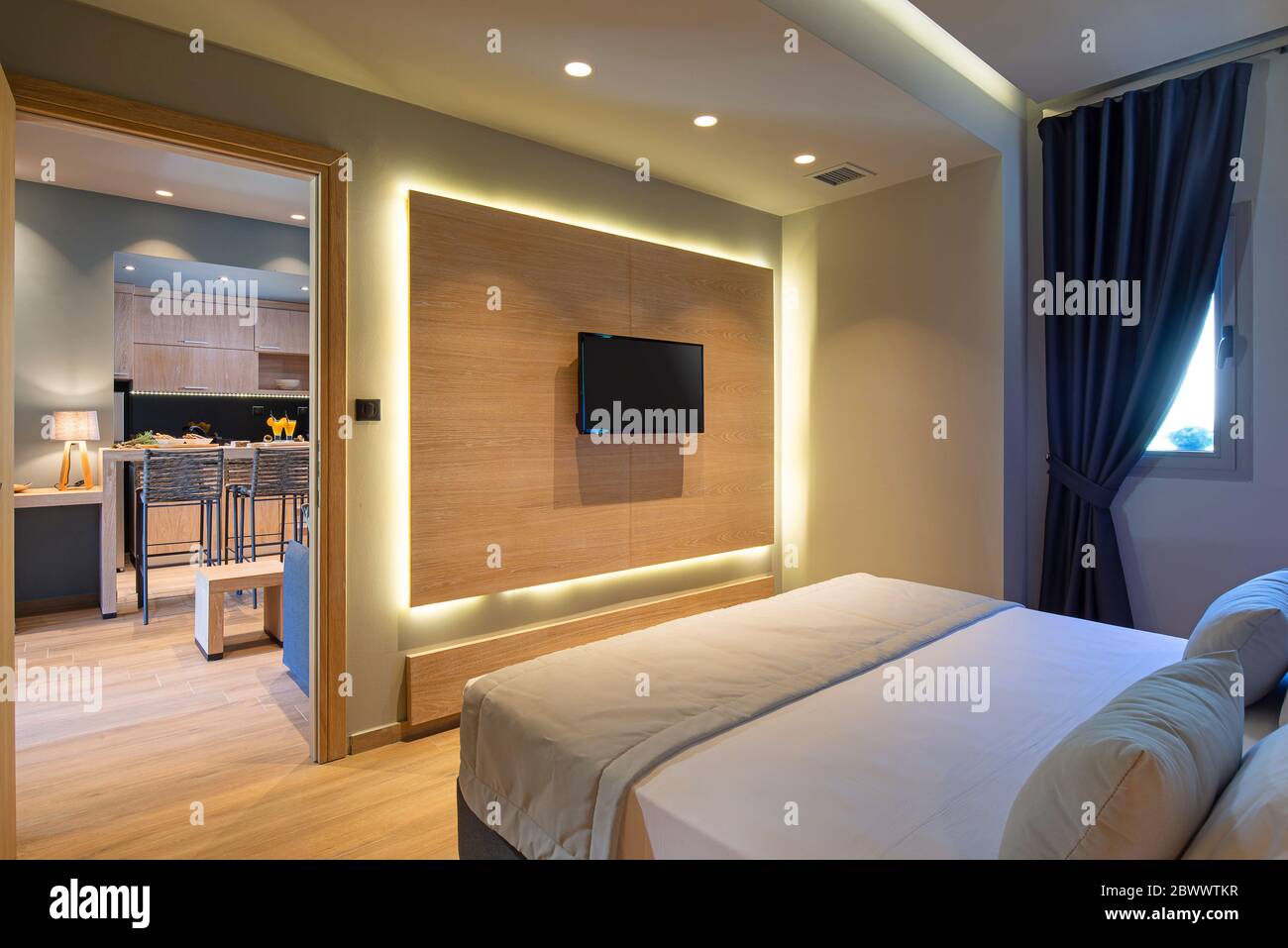 Modernes graues, blaues, hölzernes Schlafzimmer in einem kleinen Studio-Apartment. Modernes, minimalistisches Interieur des Hotel-Flat-Zimmers mit Kopierbereich und tv-Panel Stockfoto