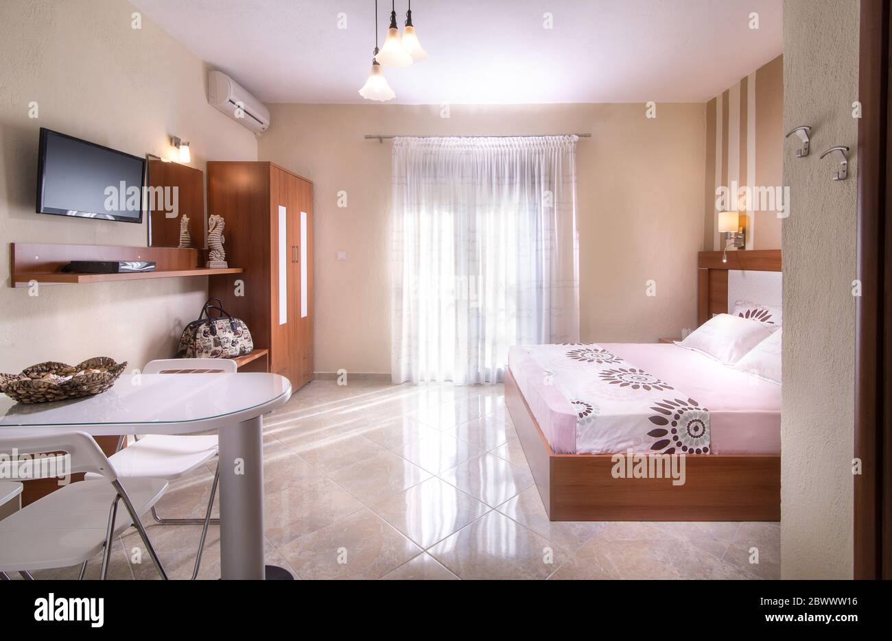 Romantisches Interieur mit schlichtem, modernem Design-Schlafzimmer mit Holzmöbeln in weiß-beigefarbenen Hotelapartments Stockfoto