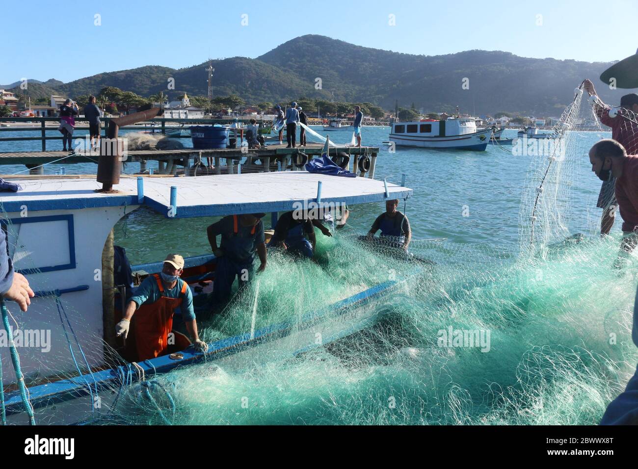 Fangnetz wird für einen neuen Arbeitstag versendet. Nachdem die gefischten Meeräschen entladen wurden, legten die Fischer das Netz wieder auf das Boot Stockfoto