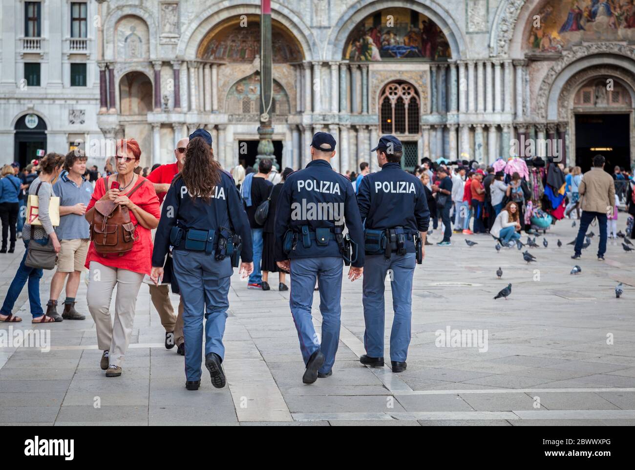 Eine weibliche und zwei männliche italienische Polizeibeamte patrouillieren unter Touristen auf dem Markusplatz in Venedig Stockfoto