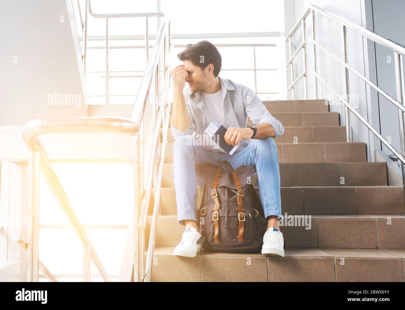 Reisebeschränkungen. Depressiver Mann Sitzt Auf Der Treppe Im Flughafen, Flug Abgesagt Stockfoto