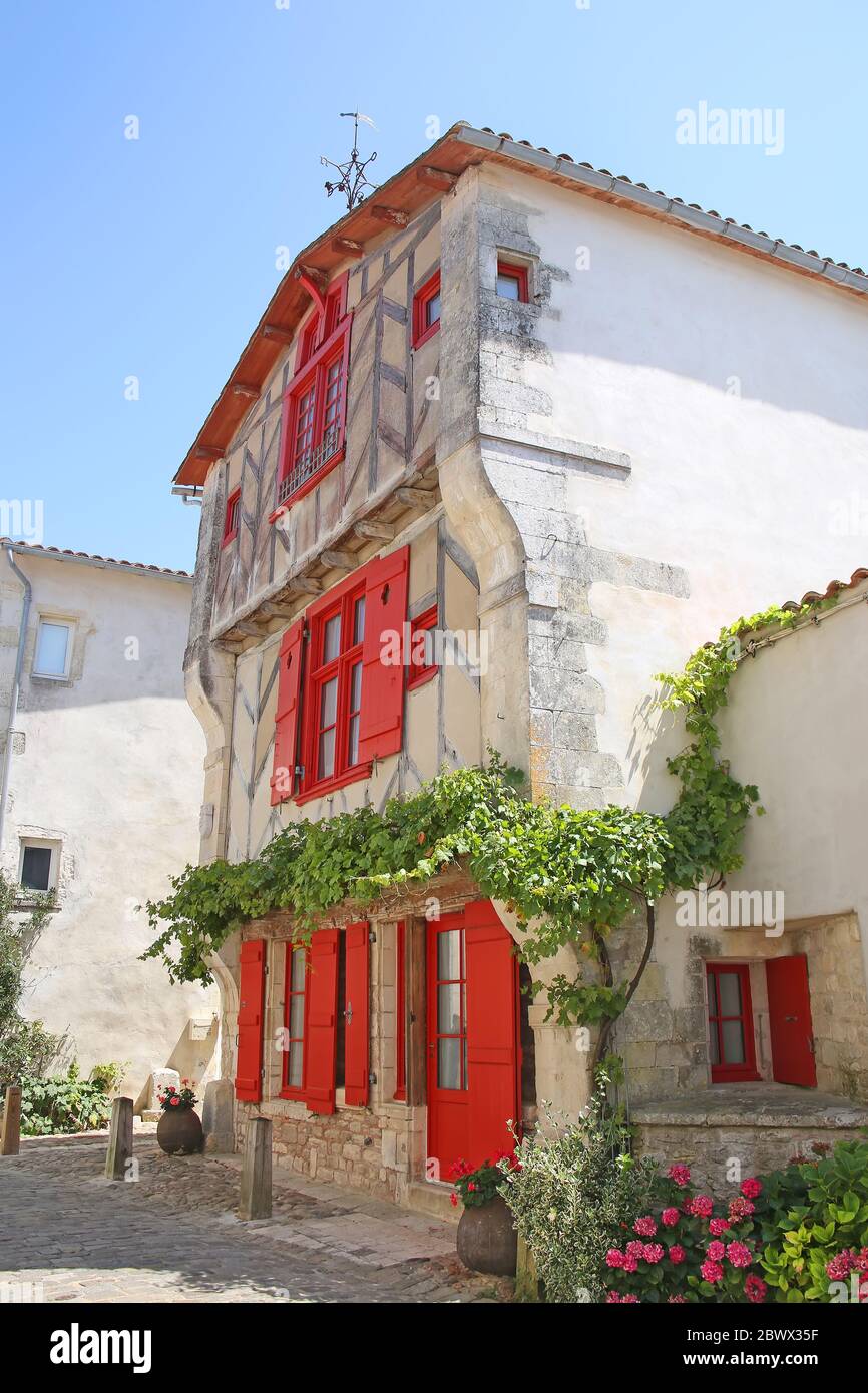 Altes rotes Fachwerkhaus mit Fensterläden und anderen historischen Gebäuden in Ile de Re, Charente Maritime, Frankreich. Stockfoto