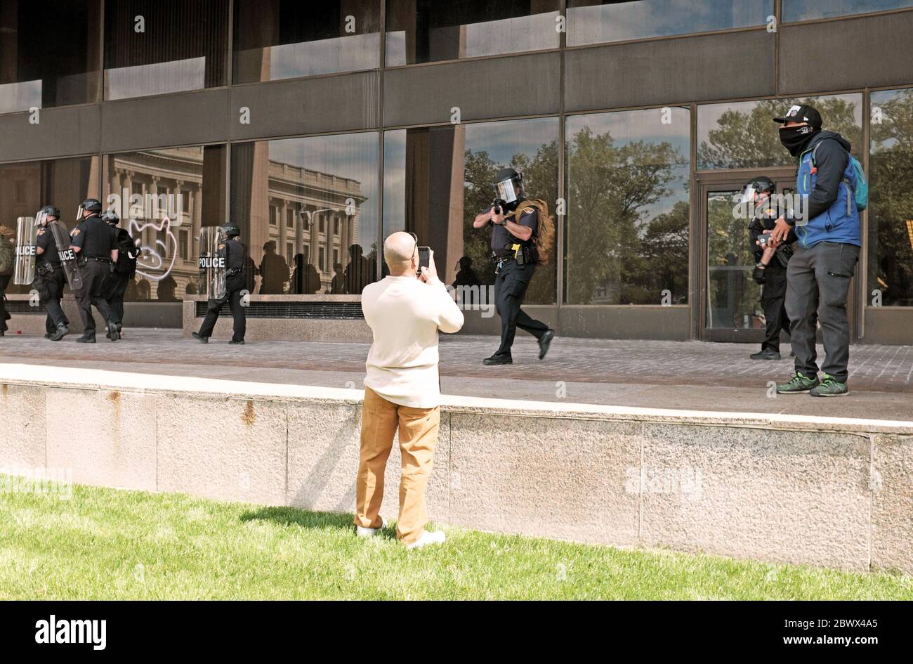 Eine Person nimmt am Telefon die Cleveland Police auf, die ihm eine Waffe zeigt, während er die George Floyd Proteste in Cleveland, Ohio, USA dokumentiert Stockfoto