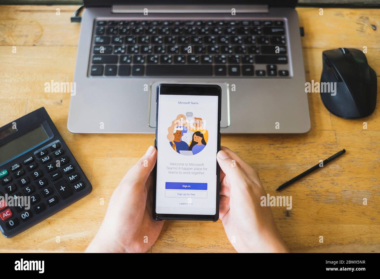 RAYONG, THAILAND - 9. MAI 2020 : Nahaufnahme der Microsoft Teams Business-Anwendung auf dem Smartphone-Bildschirm vor dem Tablet auf dem Holztisch. Anw Stockfoto