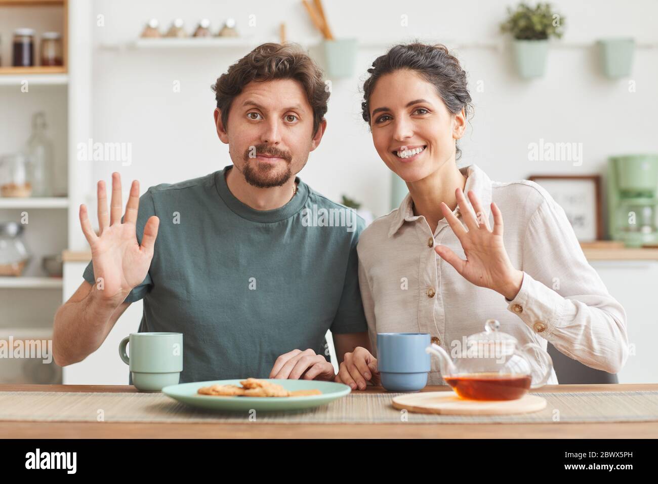 Porträt des jungen glücklichen Paar Frühstück und lächeln vor der Kamera, während am Tisch in der Küche sitzen Stockfoto