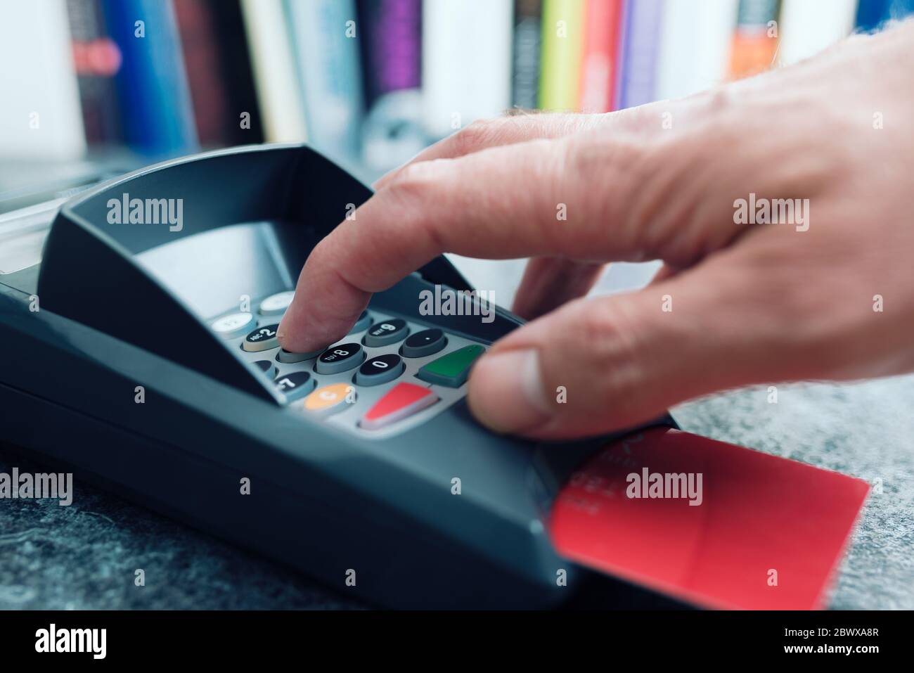 Nahaufnahme der Person, die die PIN-Nummer am POS-Zahlungsterminal für Kreditkarten eingibt Stockfoto