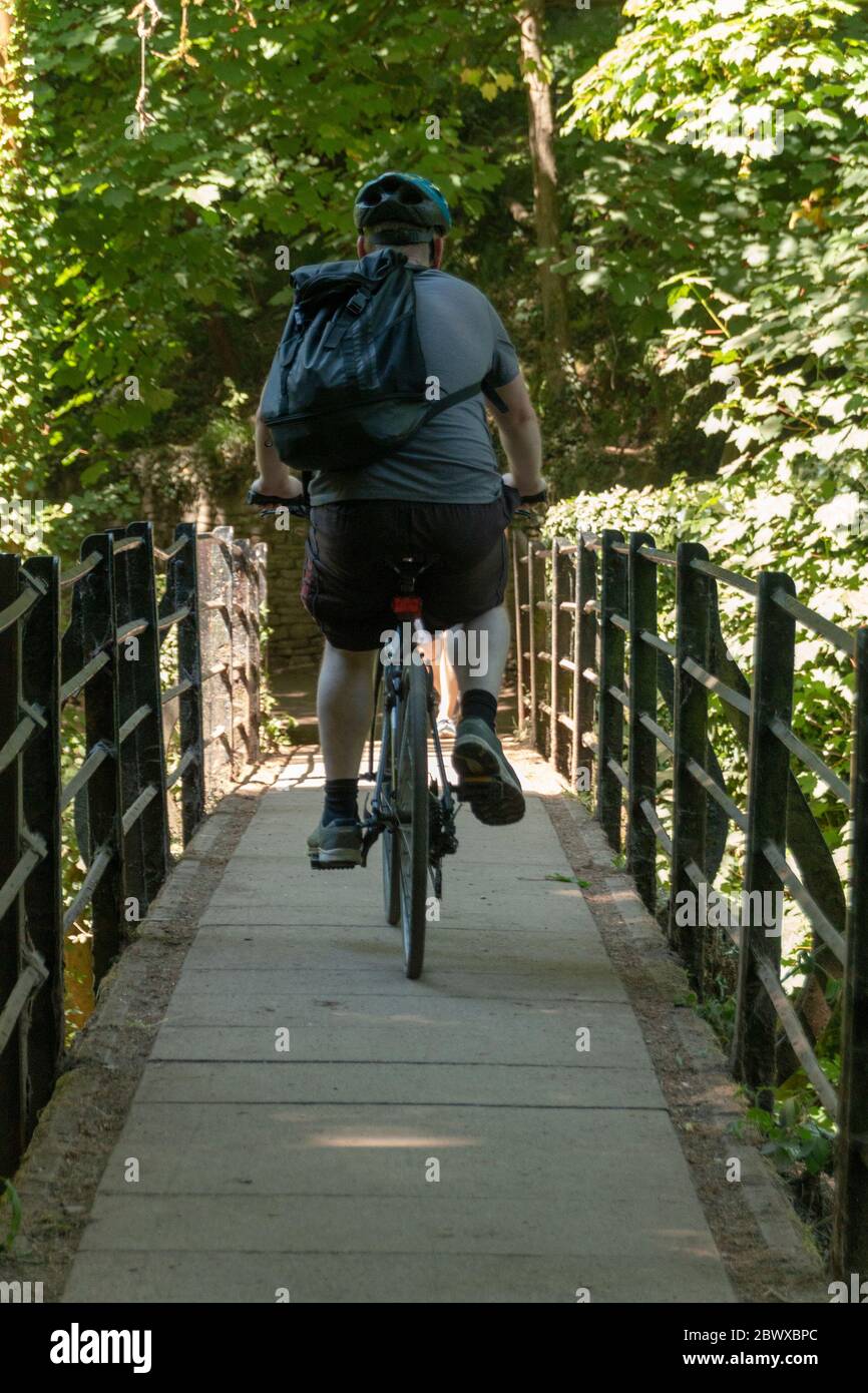 Bristol-June-2020-England-ein Nahaufnahme eines Mannes, der sein Fahrrad über eine kleine Brücke in einem öffentlichen Wald fährt Stockfoto