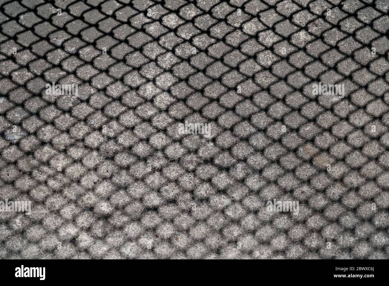 Schatten des Metallkettenzauns auf dem Boden. Stockfoto