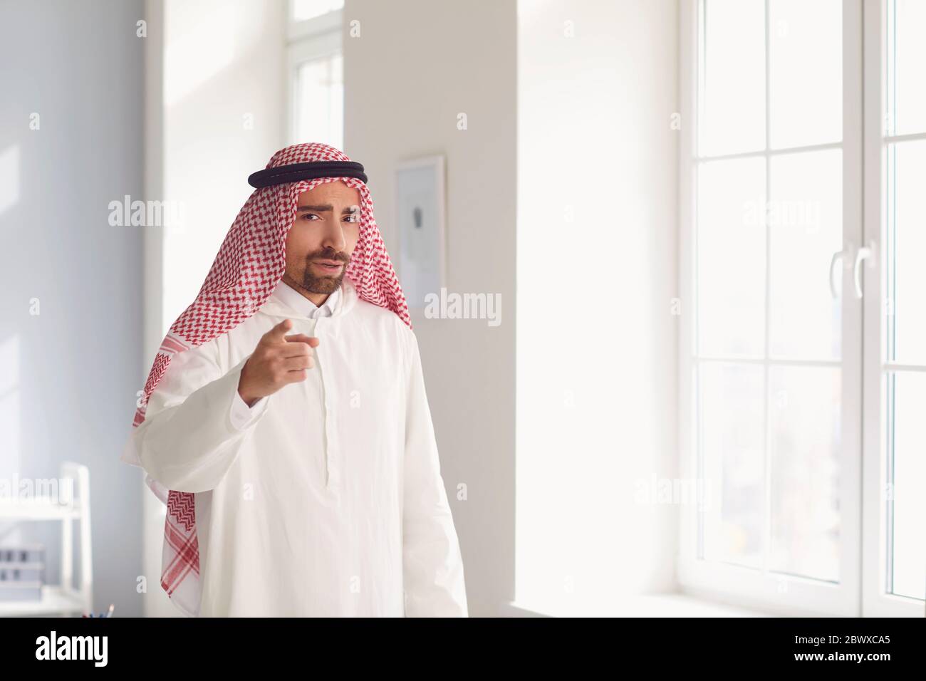 Arabischer Geschäftsmann zeigt mit dem Finger auf einen grauen Hintergrund Stockfoto