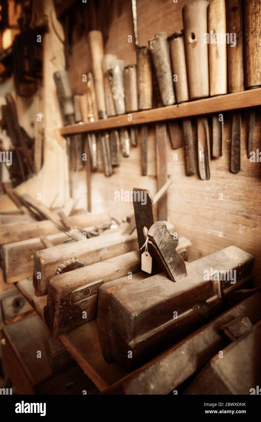 Vintage-farbiges Bild von Tischlerwerkzeugen an der Wand und Bank einer staubigen Werkstatt Stockfoto