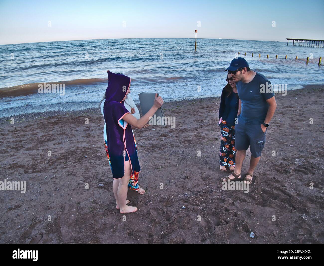 Neue normale sozial distanzierte Begegnung der Großfamilie. Onkel und Tante schauen sich die Kunstwerke ihrer Nichte beim ersten Treffen seit der Sperrung an. Stockfoto