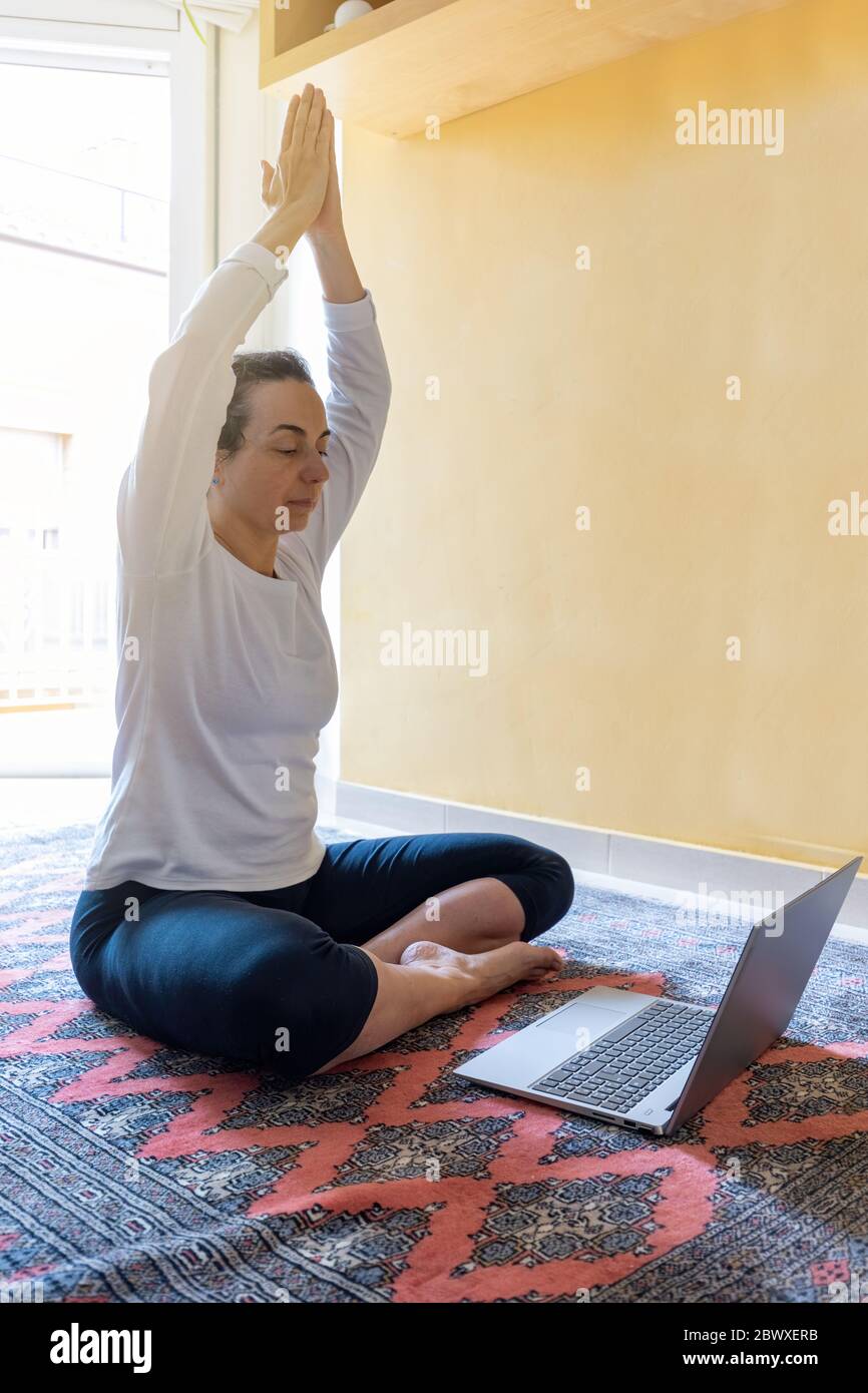 Hübsches spanisches Mädchen praktiziert Yoga zu Hause im Wohnzimmer Stockfoto