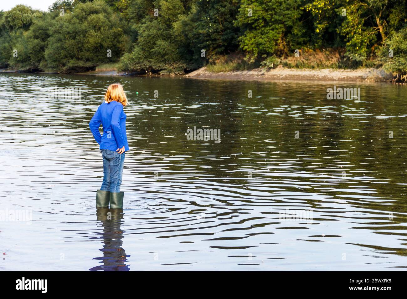 Ein dreizehnjähriges Mädchen in wellington Boots watet in Isleworth, London, Großbritannien, auf der Themse Stockfoto
