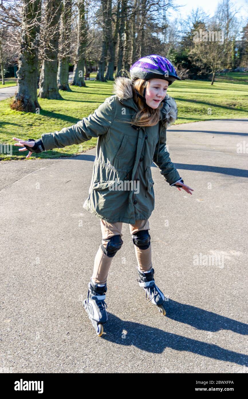 Ein dreizehn Jahre altes Mädchen, das im Park in London an Rollerblades praktiziert Stockfoto